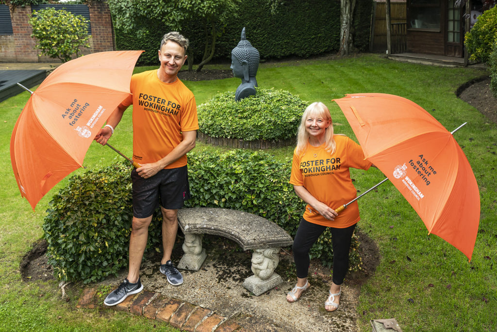 Ian Waite and foster carer Sue Rayment in a garden holding umbrellas